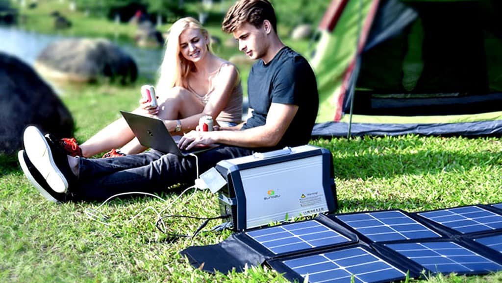 Couple-Sitting-On-The-Grass-Next-To-The-Solar-power-Bank